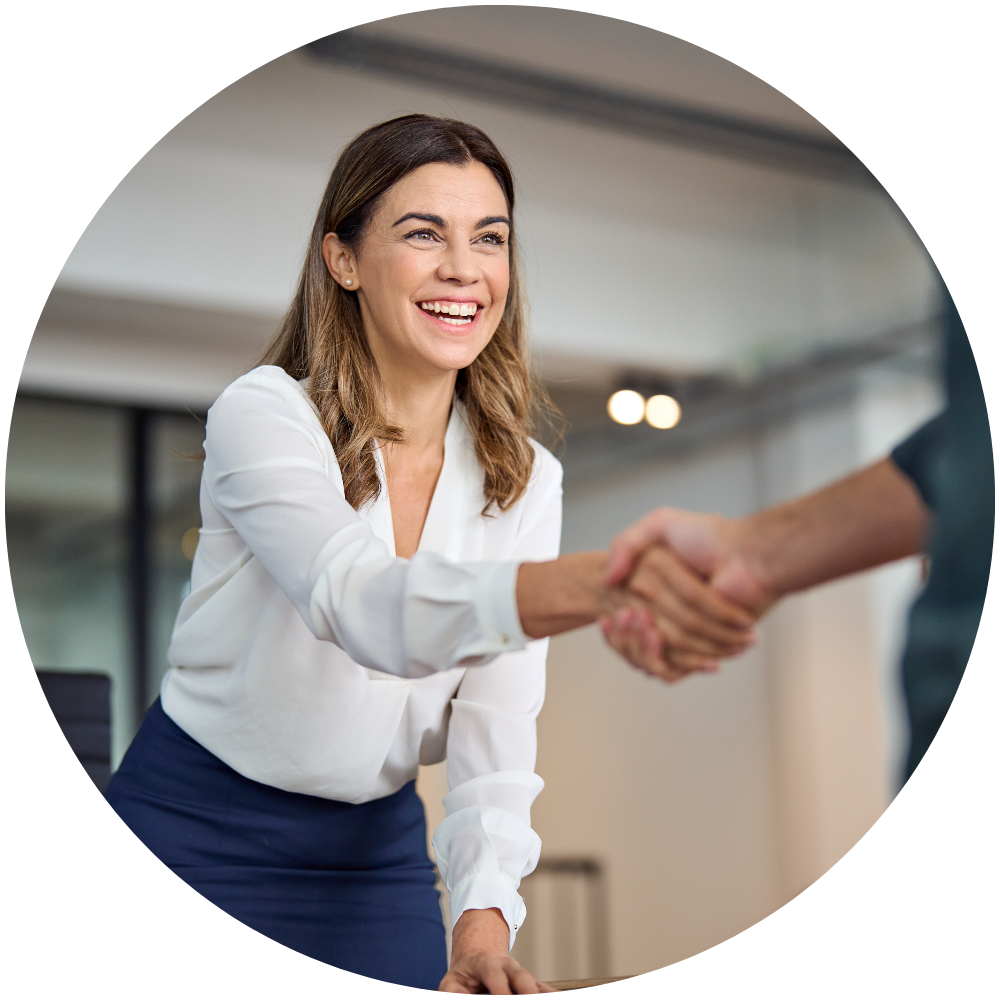 Leadership and Coaching A woman with light brown hair, wearing a white shirt, shacking someone's hand and smiling